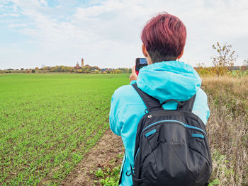 Rear view of woman standing on field against sky