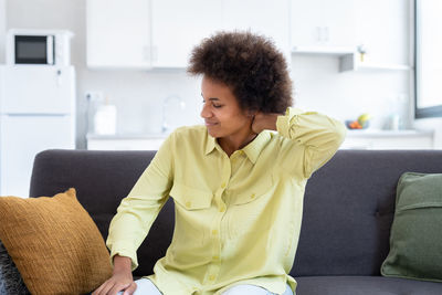 Young woman using phone while sitting on sofa at home