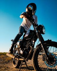 Low angle view of man sitting on motorcycle against sky