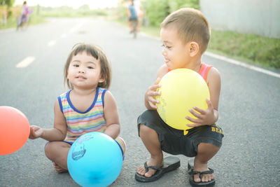 Siblings playing with balloons on road