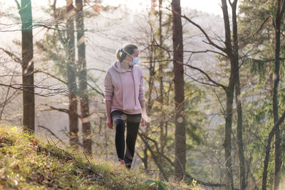 Full length of woman standing amidst trees in forest