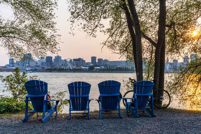 Empty chairs against trees and buildings in city