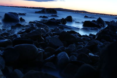 Rocks on beach against sky during sunset