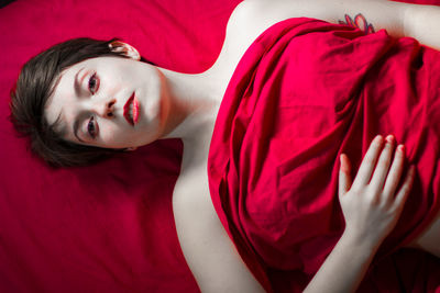 Portrait of beautiful young woman lying on bed