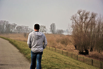 Rear view of a man standing on bare trees