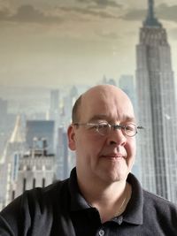 Portrait of man wearing sunglasses against buildings in city