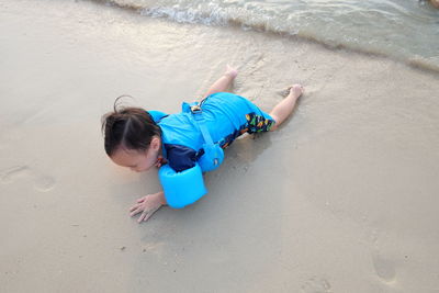 High angle view of boy playing on sand at beach