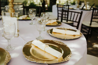 Beautiful outdoor receprion venue - white tablecloths, golden plates, white roses centerpieces