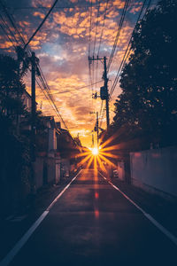 Road amidst trees against sky during sunset