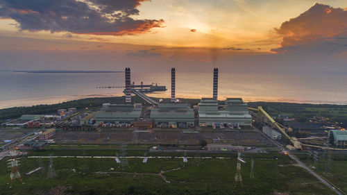 High angle view of industry by buildings against sky during sunset