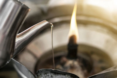 Close-up of oil pouring in burning diya