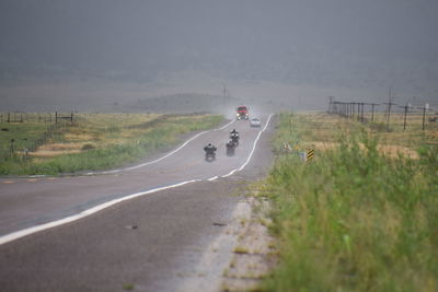 People riding motorcycle on road against sky