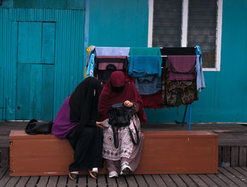 Rear view of people sitting on wall