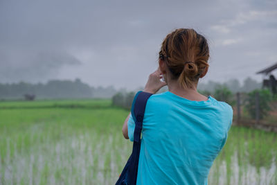 Rear view of woman standing on field against sky