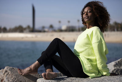 Portrait of young woman sitting on retaining wall