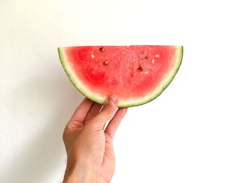 Close-up of hand holding apple against white background