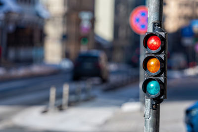 Close-up of small traffic semaphore with red light against the backdrop of the city traffic