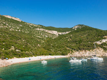 Scenic view of sea and mountains against clear blue sky