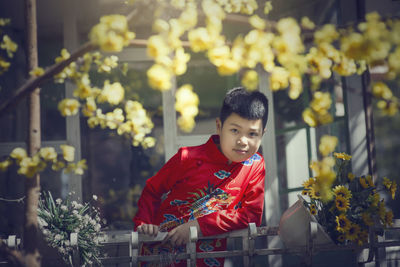 Happy boy standing by red flowering plants