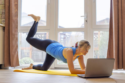 Side view of young woman exercising in gym