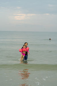 Cute sibling standing amidst sea