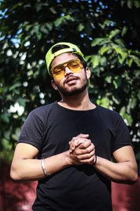 Young man wearing hat standing against plants