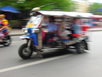 Blurred motion of people riding motorcycle on street in city