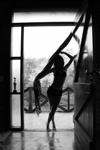 Full length of sensuous young woman standing at doorway