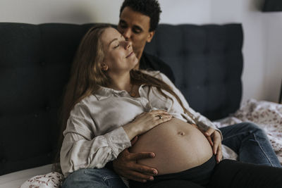 Pregnant woman with partner sitting in bed