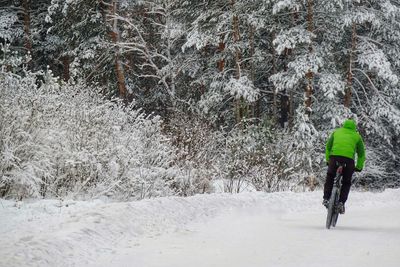 Rear view of man walking on snow covered land