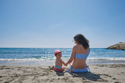 A young mother playing with her baby on the seashore. concept of reconciliation, play, love, holiday