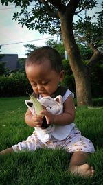 Baby girl holding leaf while sitting on grassy field