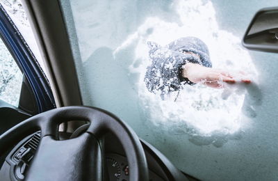 Man removing snow from car windshield