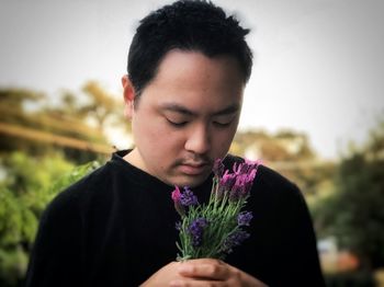 Portrait of young man holding purple flower