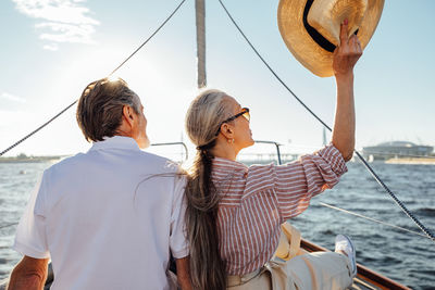 Rear view of women sailing on boat in sea against sky