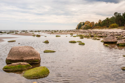 Scenic view of rocks by sea against sky