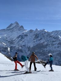 People walking on snowcapped mountain against sky