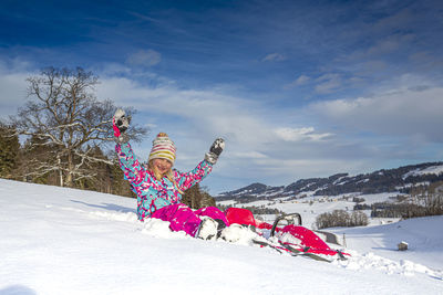 Girl on snow covered field against sky