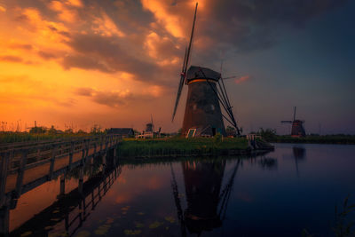 Scenic view of lake with windmill against sky during sunset