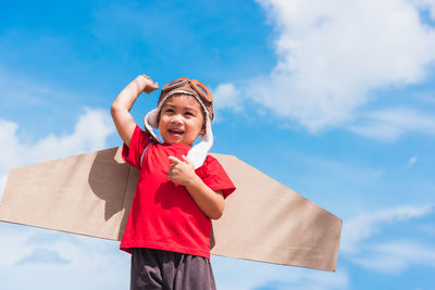 Low angle view of smiling boy standing against sky