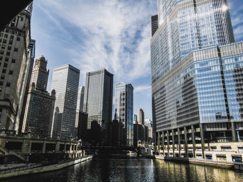 Low angle view of skyscrapers against cloudy sky