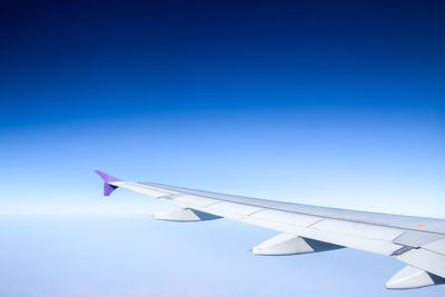 Close-up of airplane wing against clear blue sky