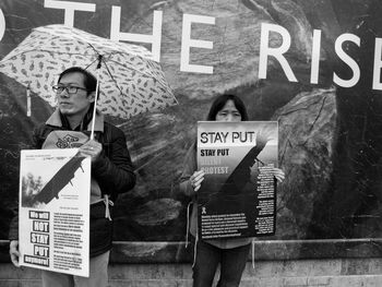 People holding signboard against wall