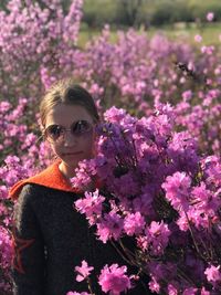 Portrait of woman standing by pink flowering plants
