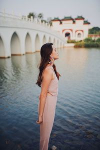 Side view of young woman standing by lake