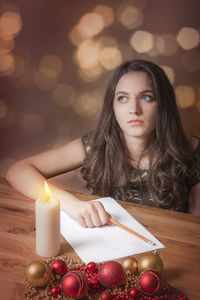 Thoughtful young woman writing on paper during christmas