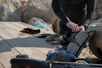 Midsection of man removing diving flipper