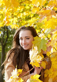 Portrait of woman standing amidst autumn leaves at park