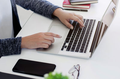 Midsection of woman using laptop on table