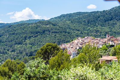 Aerial view of townscape by mountain against sky